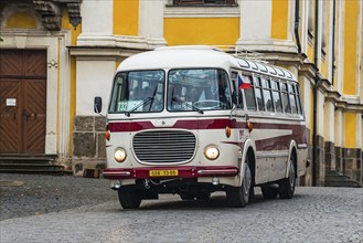 A traditional bus in front of a magnificent yellow historical building in an urban environment,