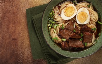 Asian noodles in broth, with beef and egg, top view, close-up, no people