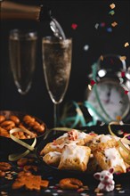 New Year's Eve, pastries and champagne glasses on a table, pouring champagne