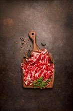 Prosciutto on a cutting board, top view, appetizer, breakfast, spices and herbs