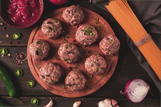 Raw meatballs, with micro greenery, with spices and ingredients, on a wooden table, homemade,