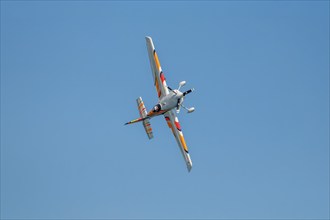 Stunt aerobatic plane performing stunts in blue sky. Concept of speed, difficulty, precision, risk,