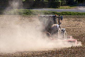 Tractor with plough digging up dried-out soil, large cloud of dust, dust, dry, field, earth,