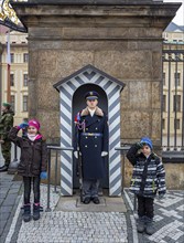 Two children salute next to the castle guard, Prague, Czech Republic, Europe