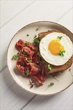 Breakfast, fried egg with bacon, micro-green, on a light background, no people, selective focus