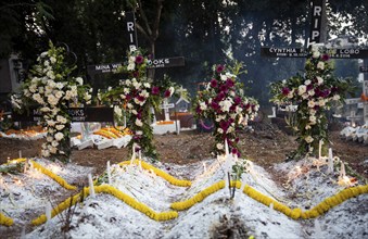 People from Christian community light candles and offer prayers on the grave of their relative