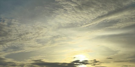 Evening sky with veil clouds Cirrostratus, on the right Cirrus feather clouds shine in yellow light