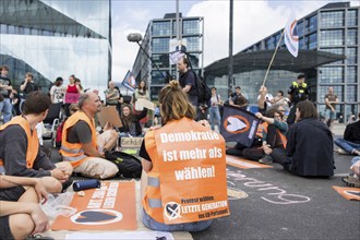 Last Generation activist with poster Democracy is more than voting! for the upcoming European