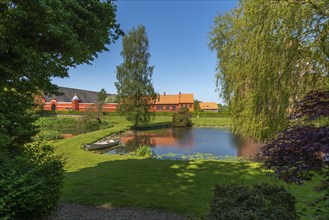 Farm building of Hesselagergaard Manor with park, lake, rowing boat, Fyn, Fyn Island, Denmark,