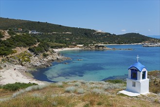 Small chapel with blue roof on a rocky coast with clear sea water, Greek Orthodox shrine, beach