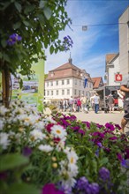 Street scene with a green flower arrangement in the foreground and people in an urban environment