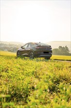 SUV driving through a green rural environment with a sunny background, VW ID5 electric car, Calw,