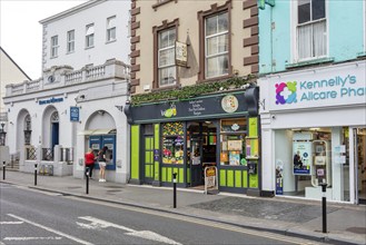 Shops and pharmacy along a busy street with mixed historic and modern facades, Tralee