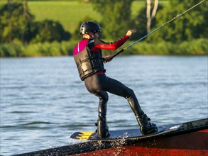 Young man with wakeboard on obstacle, water sports, water skiing in wakepark