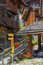 Hiking trail with signposts leads through the historic village centre, Grimentz, Val d'Anniviers,