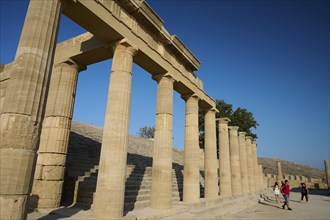 Super wide angle shot, tourists walking next to the imposing columns of an ancient ruin under a