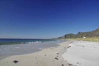 Beautiful beach with clear blue sky, gentle waves and mountains in the background, Bleik,