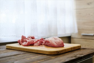 Raw pork shoulder on wooden cutting board in the kitchen