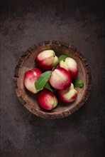 Ripe nectarine, in a wooden plate, brown background, top view, no people