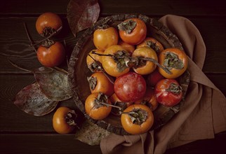 Fresh persimmon, in a wooden plate, top view, no people