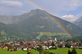 View over Oberstdorf with rainbow, behind it the Schattenberg with Schattenbergschanze, Oberallgäu,