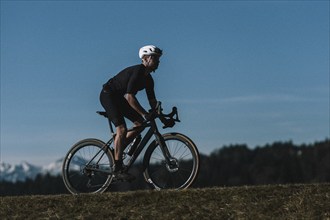 Road bike rider in spring near Halblech in the Allgäu in front of a picturesque backdrop of the