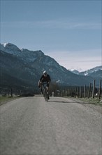 Road bike rider in spring near Halblech in the Allgäu in front of a picturesque backdrop of the