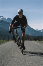 Road bike rider in spring near Halblech in the Allgäu in front of a picturesque backdrop of the