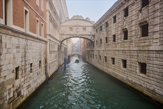 View from 'Ponte della paglia' on the bridge 'Bridge of Sighs' over a waterway before sunrise in