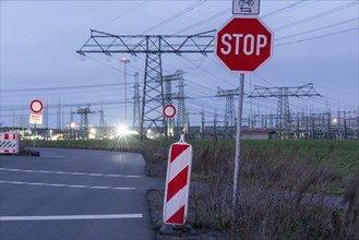 Road with stop sign and high-voltage pylons in the background, evening mood, Wolmirstedt,