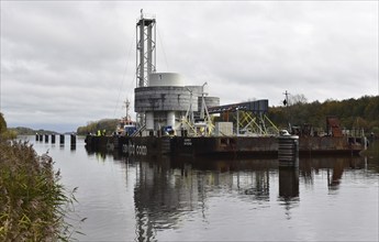 Tugboat towing a pontoon with offshore installation in the Kiel Canal, Schleswig-Holstein, Germany,