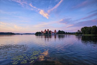 Trakai Island Castle in lake Galve, Lithuania on sunset with dramatic sky reflecting in water.