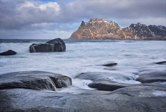 Rocks on beach of fjord of Norwegian sea in winter with snow. Utakliev beach, Lofoten islands,