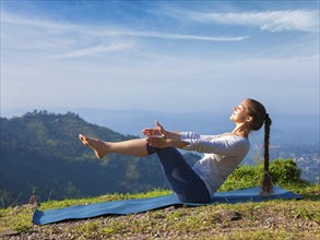 Yoga outdoors, young sporty fit woman doing Ashtanga Vinyasa Yoga asana Navasana, boat pose easy