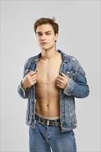 Young man in denim clothes ober naked body