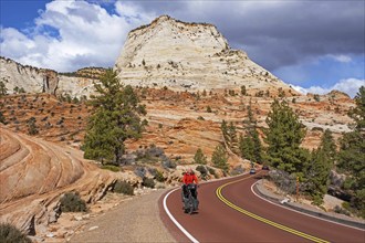 Solitary touring cyclist cycling through the red sandstone mountains of Zion National Park, Utah,