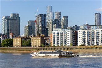 Uber boat water bus service passing Canary Wharf, Isle of Dogs, London, England, UK