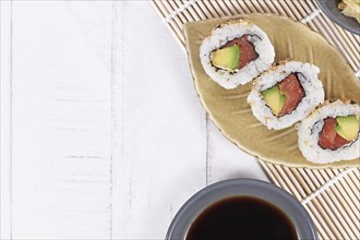 Sushi inside out rolls with salmon, avocado and sesame on small leaf shaped plateSushi inside out