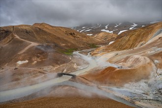 Steaming streams and bridge between colourful rhyolite mountains, Hveradalir geothermal area,