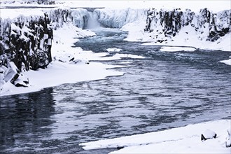 Selfoss waterfall with the river Jökullsa a Fjöllum, icy and snow-covered cliffs and shoreline,