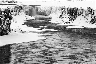 Selfoss waterfall with the river Jökullsa a Fjöllum, icy and snow-covered rock faces and shoreline,