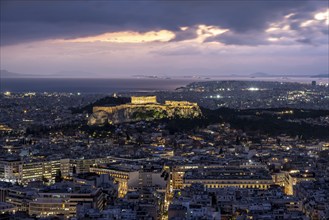 View over the sea of houses of Athens, illuminated Parthenon temple on the Acropolis, dramatic