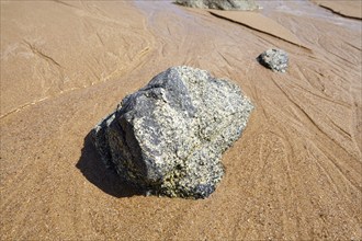 Stones in receding water at low tide on the beach at Plévenon, Côtes-d'Armor, Brittany, France,