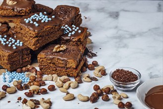 Brownies filled with jam and ingredients for decoration, chocolate icing, nut mix, chocolate