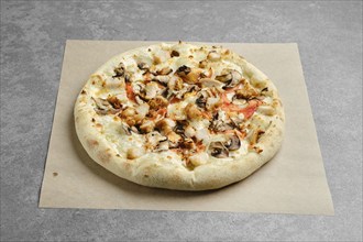 Pizza with chicken breast and champignon mushrooms on parchment paper