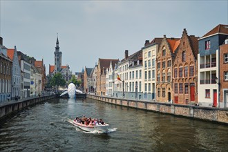 BRUGES, BELGIUM, MAY 29, 2018: Tourist boat in canal between old houses with The Bruges Whale