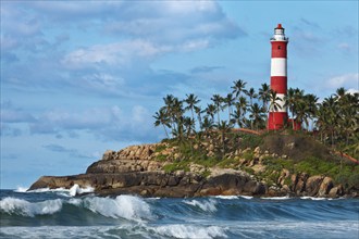 Lighthouse on rocky cliff and sea with waves