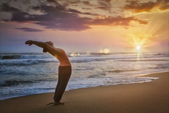 Young sporty fit woman doing yoga Sun salutation Surya Namaskar pose Hasta Uttanasana on tropical