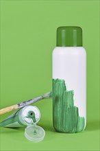 Greenwashing concept with white plastic bottle being painted green