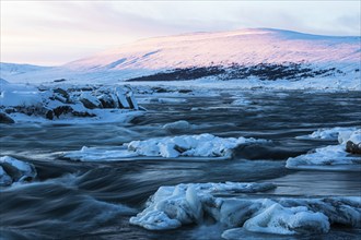 Ice blocks in the river Skalfandafljot at dawn, near the waterfall Godafoss, snow-covered